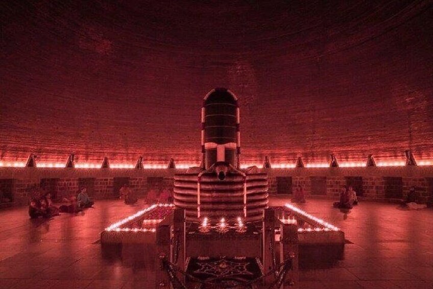 A dimly lit room with a central structure resembling a chair or throne, surrounded by brick walls and illuminated by red lighting. 4