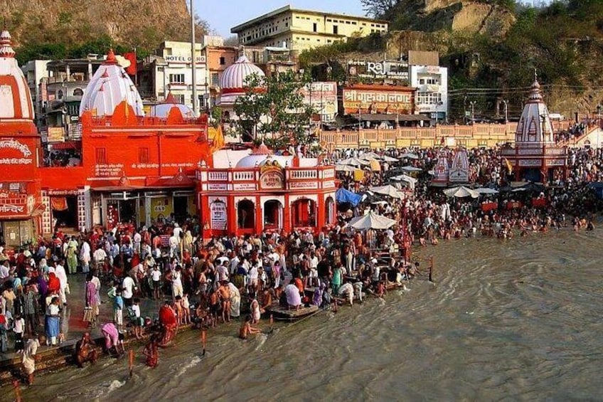 A crowded riverside with traditional buildings and a large gathering of people. 1