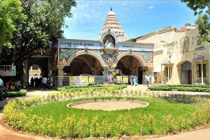 A temple with a central dome, a courtyard with a circular garden, and a building with a sign. 1