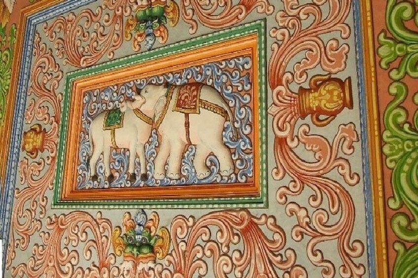 A detailed ceiling with ornate patterns and a central framed depiction of two elephants. 3
