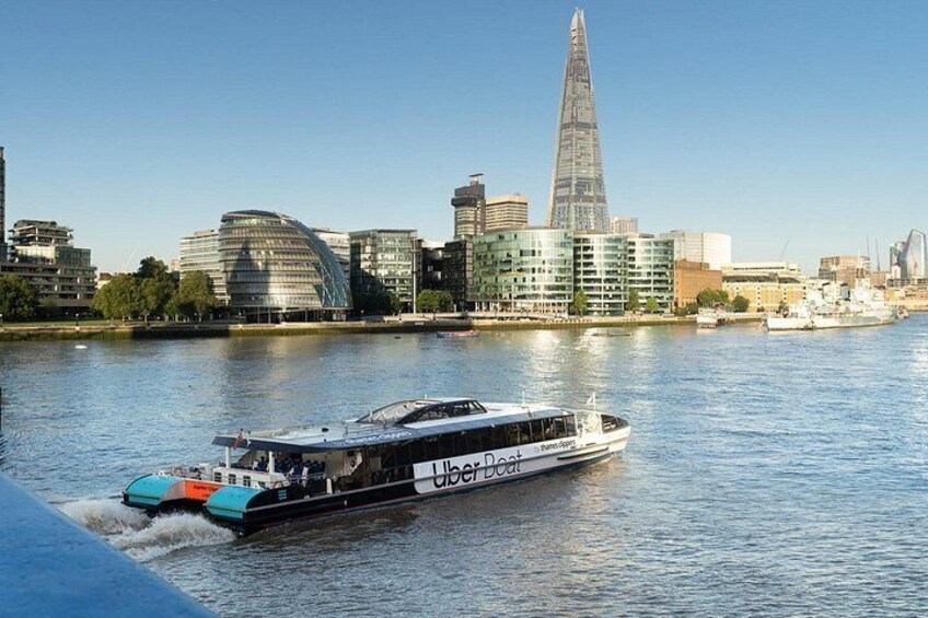 Een rivier met een boot genaamd 'Uber Boat' en een stadsachtergrond. 2