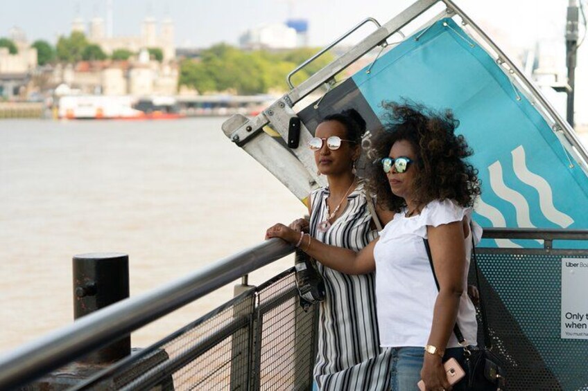Two people standing by a waterfront with a cityscape in the background. 2