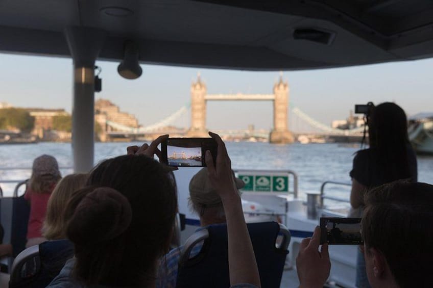 Een groep mensen op een boot maakt foto’s van een brug. 3