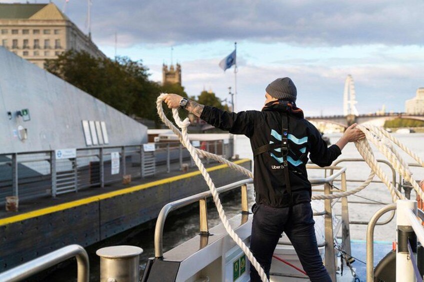 A person on a boat holding onto a rope, with a cityscape and a bridge in the background. 3