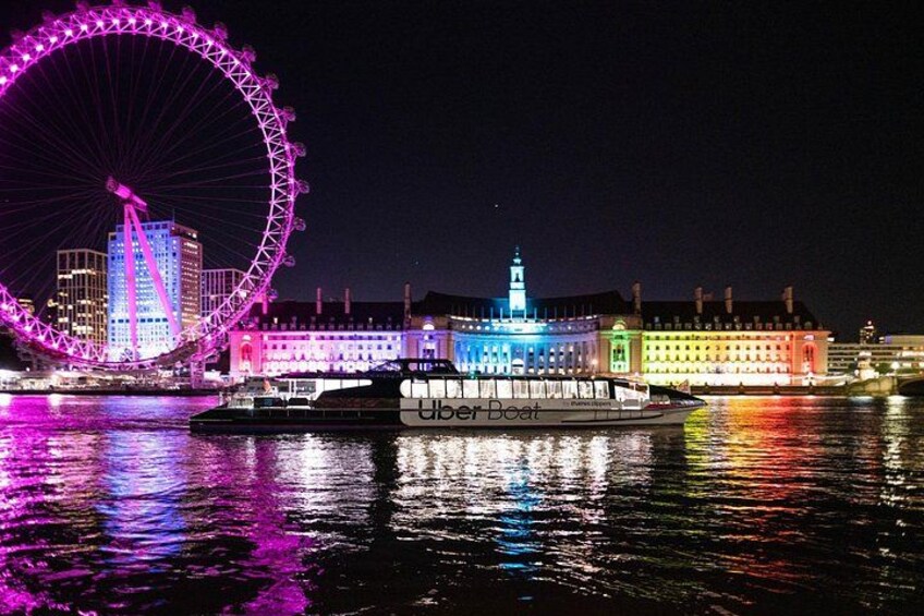 Une grande roue, un bâtiment illuminé et un bateau sur lequel on peut lire les mots « Uber Boat ». 1
