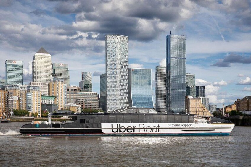 Une rivière avec un bateau portant l’inscription « Uber Boat » et, en arrière-plan, la silhouette d’une ville. 2