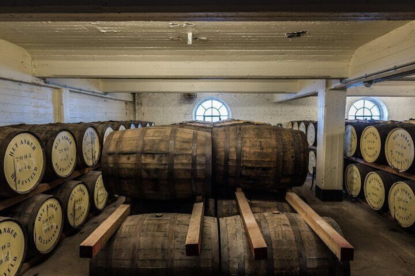 Una bodega con barriles de madera apilados contra las paredes y un barril grande en el centro. 2