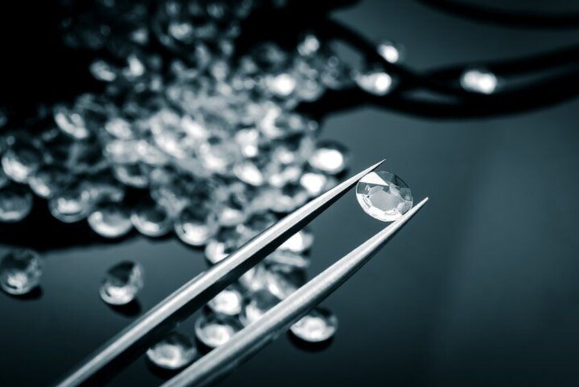 A diamond held by tweezers with other diamonds in the background. 4