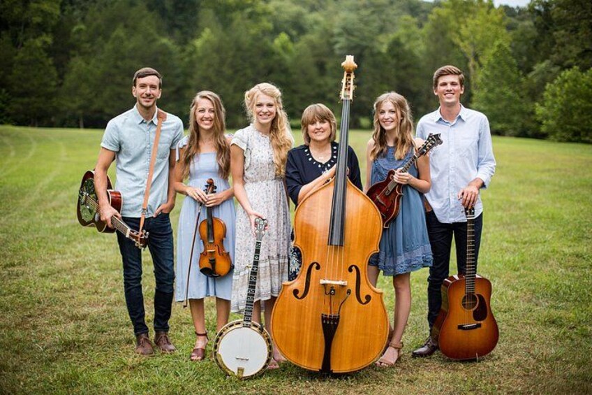 A group of people standing in a grassy field with musical instruments. 2