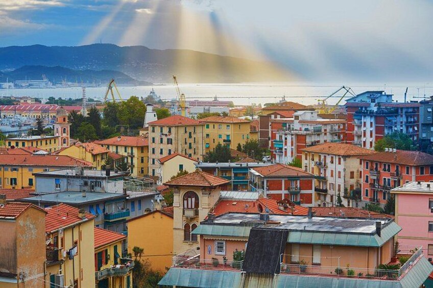 A coastal cityscape with colorful buildings, a harbor with cranes, and mountains in the distance. 2