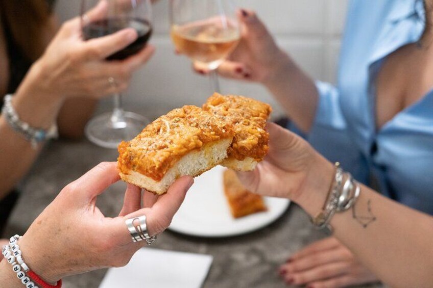 Una persona sostiene un bocado de comida, probablemente un pastel, con un plato y un vaso de bebida al fondo. 3
