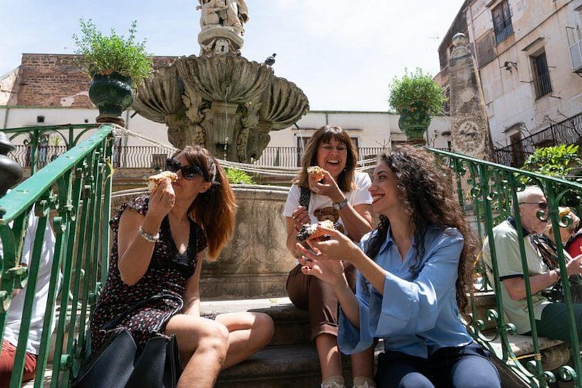 People sitting on steps with a fountain in the background. 2