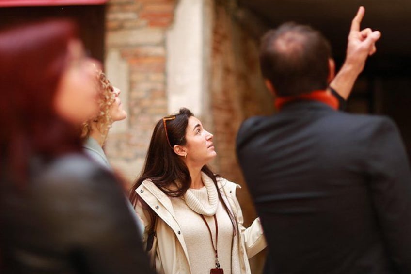 A group of people in an outdoor setting with a brick wall and a building entrance. 5