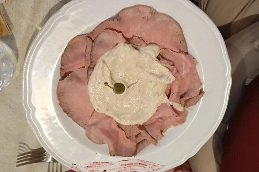 A plate of sliced ham with a dollop of cream and a cherry on top. 3