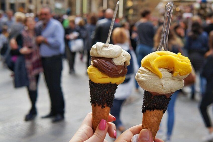 Two ice cream cones with toppings held by a person. 4