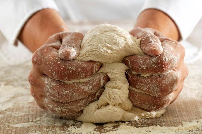 Hands kneading dough on a wooden surface. 4