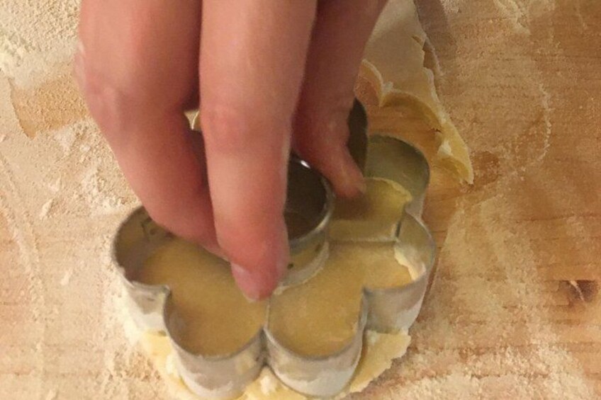 A hand using cookie cutters on dough. 3