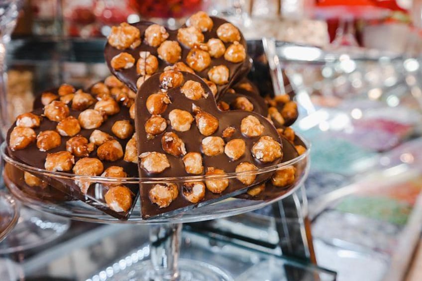 Een glazen vitrine met chocoladebedekte lekkernijen, gegarneerd met noten. 1