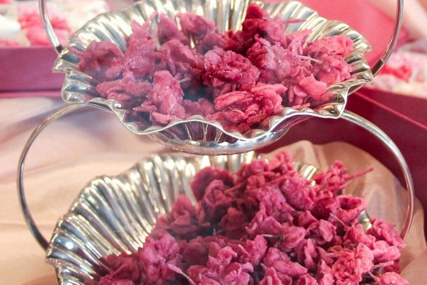 Twee metalen serveerschaaltjes vol met roze bloemen. 5