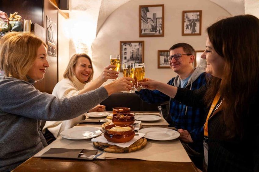 Un grupo de personas brindando con vasos de cerveza en una mesa con comida. 4