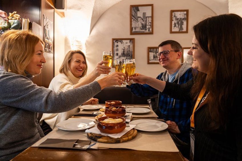 Un grupo de personas brindando con vasos de cerveza a una mesa con un plato de comida y una banana. 2