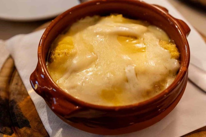 Un tazón de sopa con textura cremosa y una costra dorada en la parte superior, servido en un tazón de cerámica marrón. 5