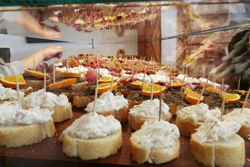 A variety of food items displayed in a glass case, including bread with cream and orange slices. 4