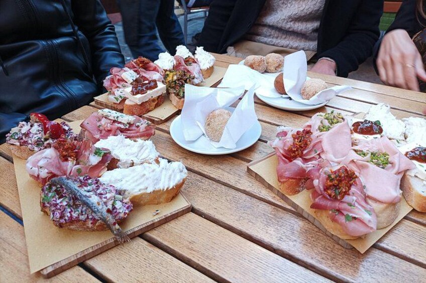 Un tavolo di legno con diversi cibi, tra cui pane farcito e carne. 4