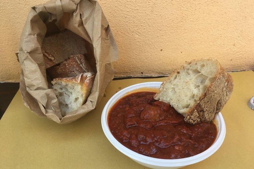 Un plato de salsa de tomate con una rebanada de pan sobre una mesa amarilla. 4