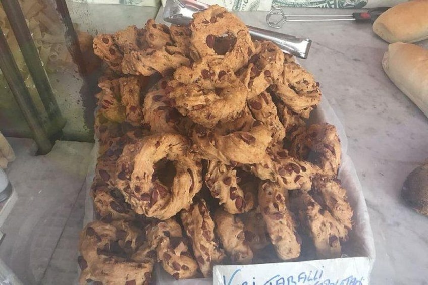 Una bandeja de rosquillas fritas con agujeros, un par de pinzas y una barra de pan. 3