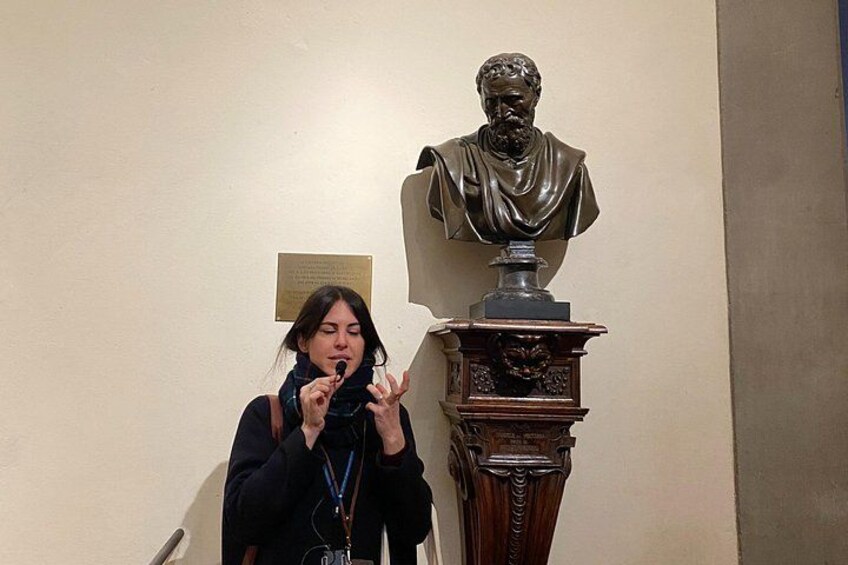 Una persona de pie junto a un busto sobre un pedestal. 3