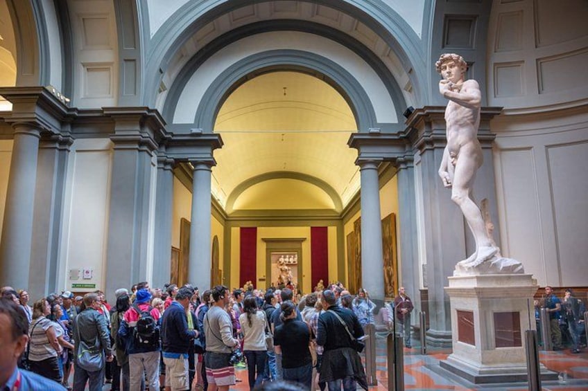Un pasillo de museo concurrido, con estatuas clásicas y columnas. 4