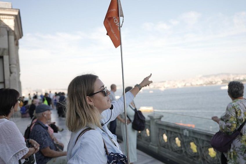 A person pointing towards a body of water with a flag on a pole. 5
