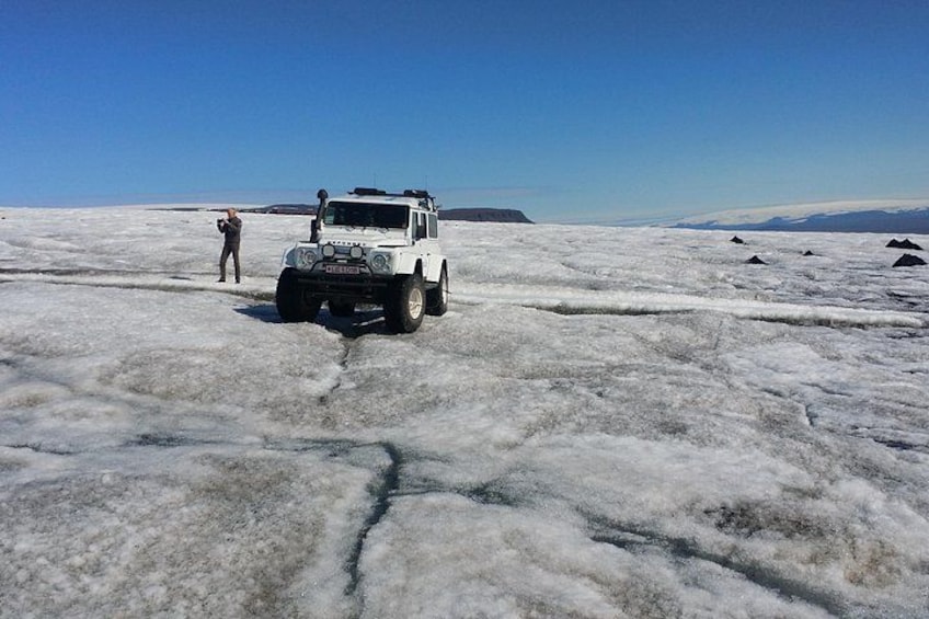 A white vehicle on a frozen landscape with a person standing nearby. 1