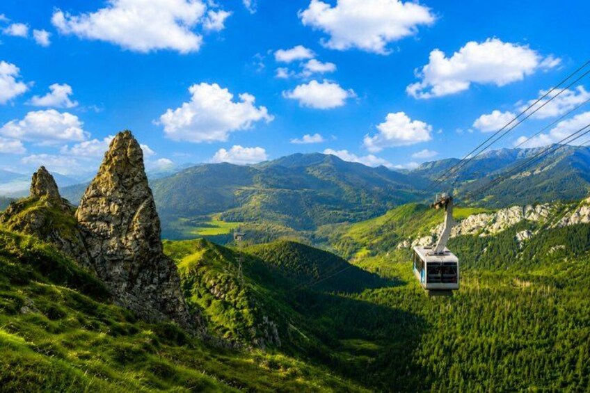 A cable car in a mountainous landscape with green valleys and rocky outcrops. 4