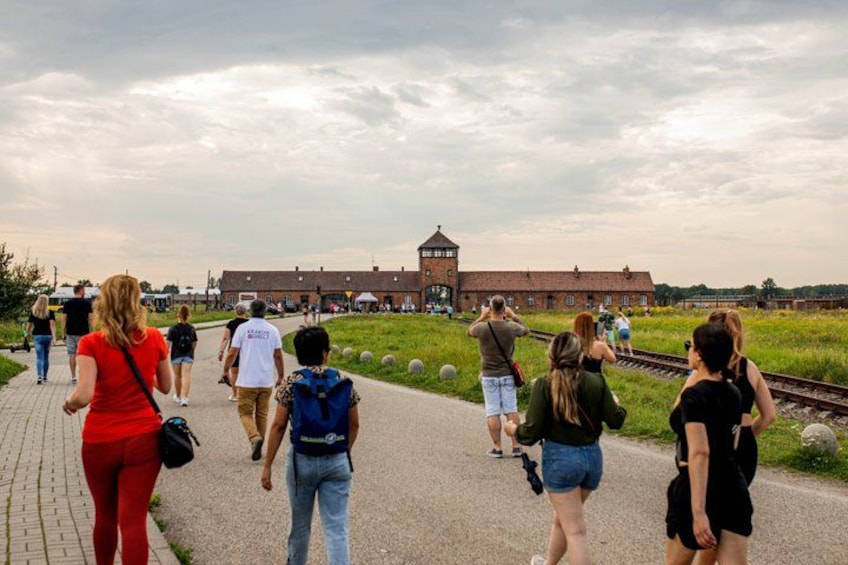 A group of people walking on a paved path towards a historic building with a tower. 2