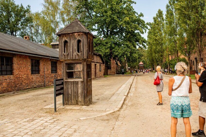 A rustic wooden structure, a brick building, and a paved path with people walking. 3