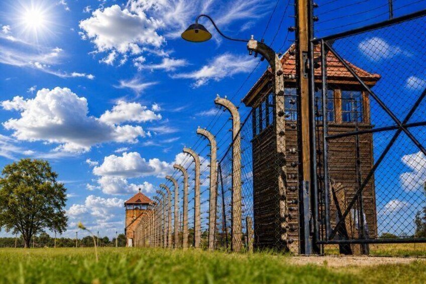 A barbed wire fence, a watchtower, and a clear blue sky. 4