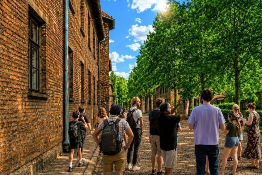 A group of people walking along a brick building with trees lining the street. 5