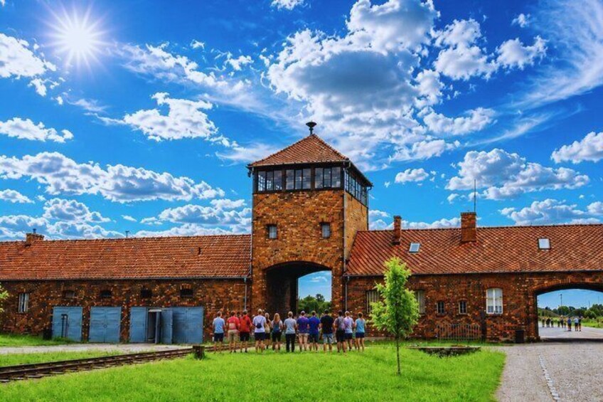 A brick building with a tower, a clear sky, and a group of people standing in front. 3