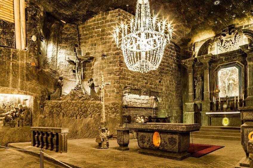 Interior de iglesia con una gran lámpara de araña, paredes de piedra y estatuas religiosas. 5