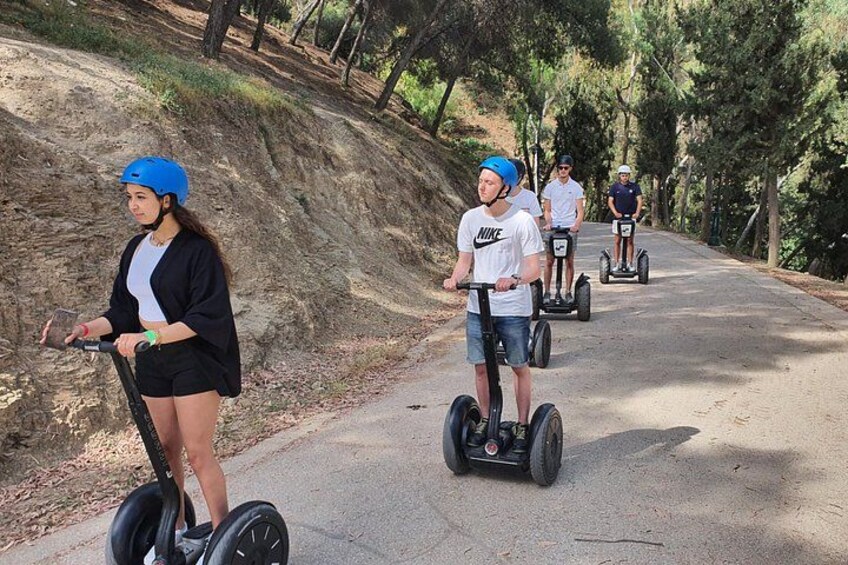 People riding segways on a paved path surrounded by trees. 4