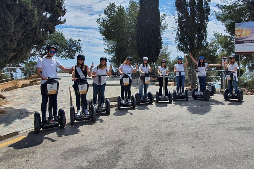 A group of people on segways in a paved area with trees and a clear sky. 2