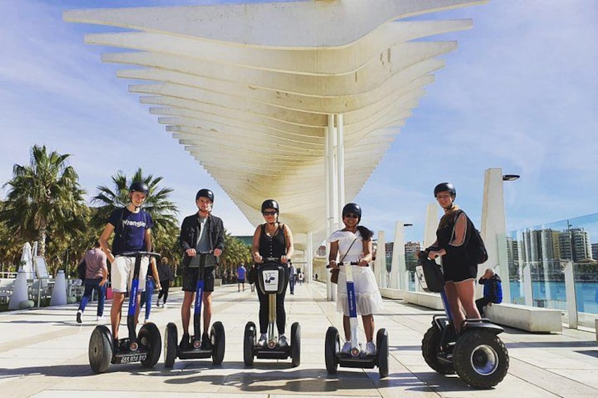 Personas en segways, una estructura con toldo blanco y palmeras. 1
