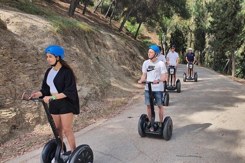 Personen rijden op segways over een verhard pad, omringd door bomen. 3