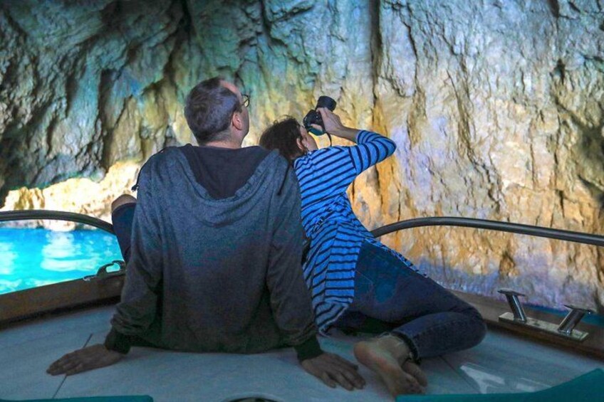 Two people sitting on a boat inside a cave with a pool. 2