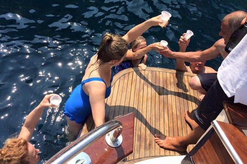 A group of people on a wooden boat, holding drinks. 3
