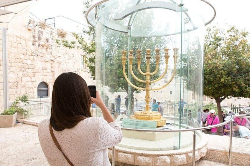 En person fotograferar en gyllene menorah inuti ett glasinneslutning. 2