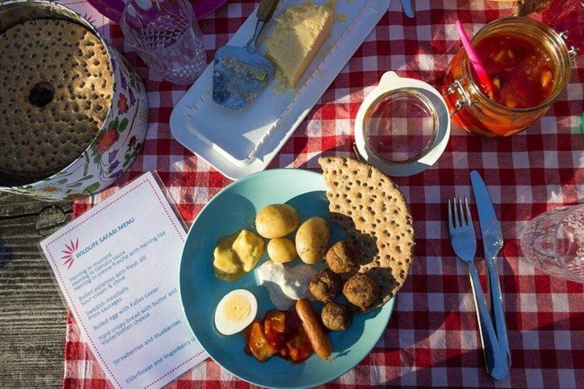 A picnic setup with a plate of food, a cake, and a menu on a checkered tablecloth. 3