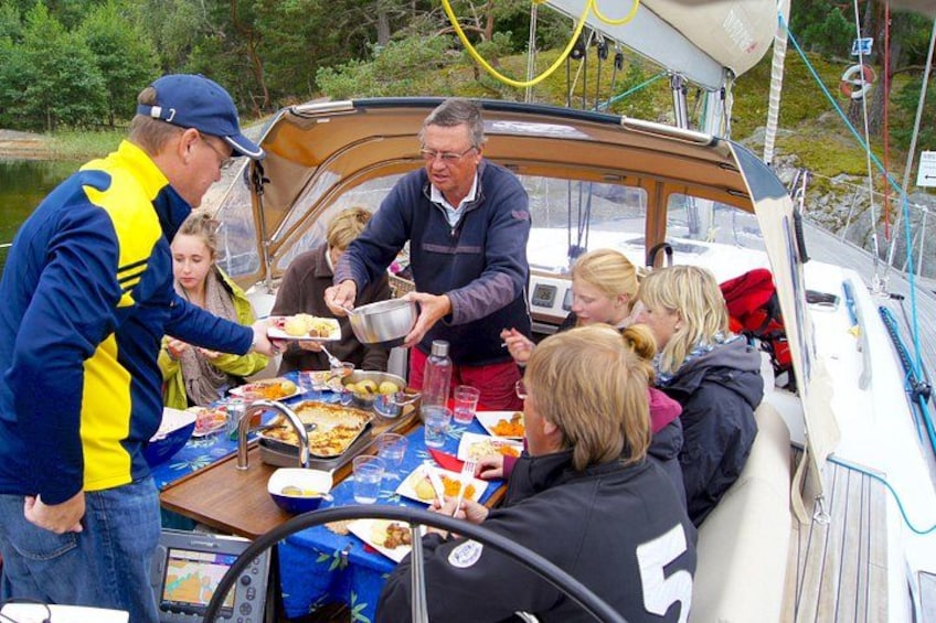 Eine Gruppe von Menschen auf einem Boot, mit Essen und Getränken auf einem Tisch. 1